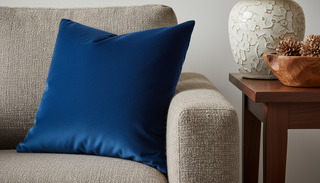 Deep blue velvet pillow on a beige sofa near some other simply textured decor